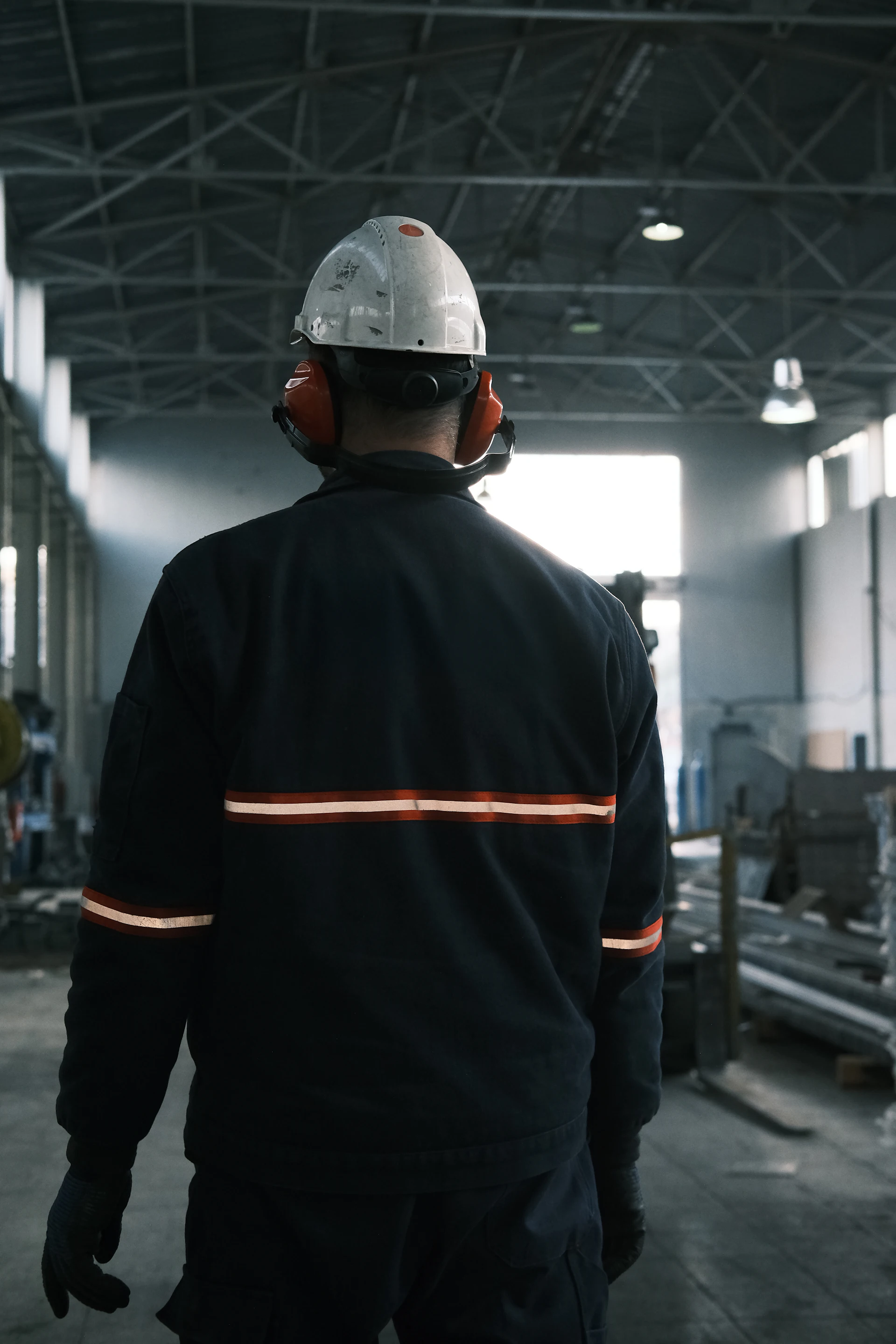 Plant operator in helmet and ear defenders walking the shop floor